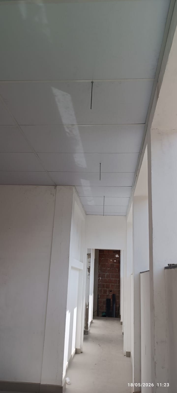 Corredor interno com instalação de drywall em paredes e forro